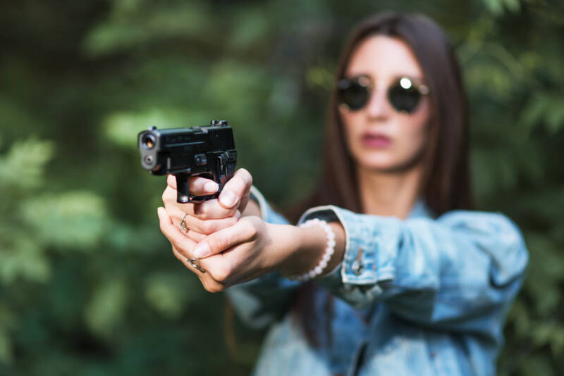 girl shooting instructor takes aim with a gun at the site
